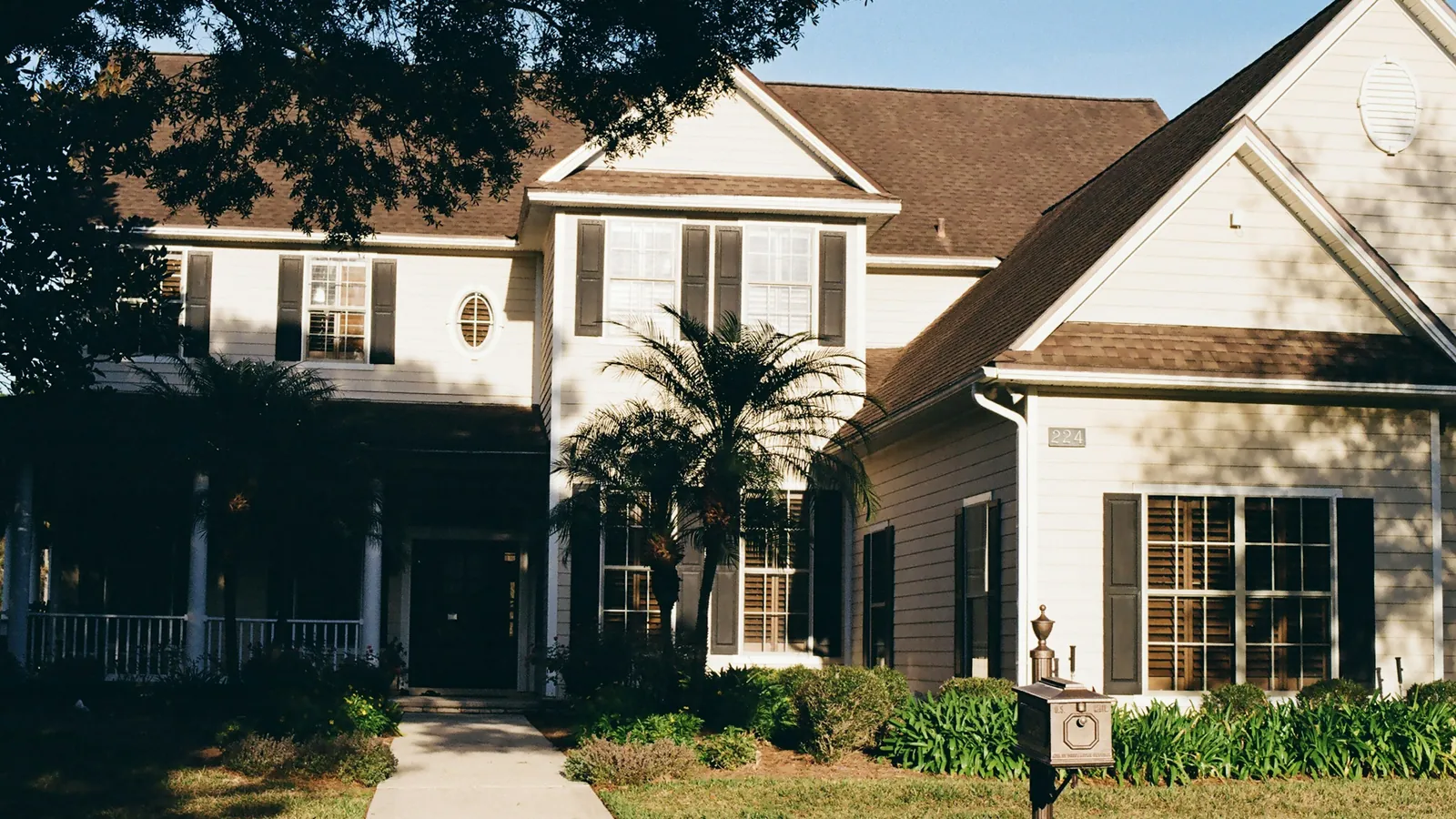 Two-storey home with an architectural shingle roof and palm trees